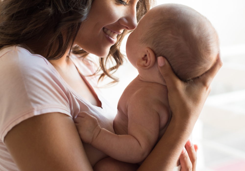 Home interior, mother and baby embrace, close-up composition, soft natural light, documentary style, people present.
