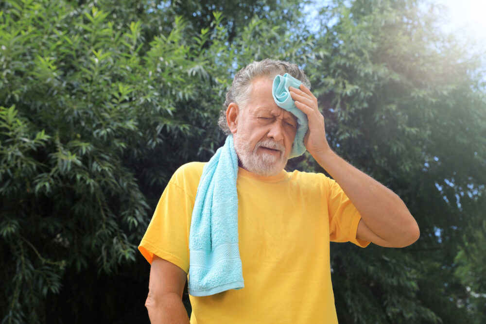 Outdoors, older man in yellow shirt, mid-frame closeup, midday sunlight with trees, editorial travel photo, one person.