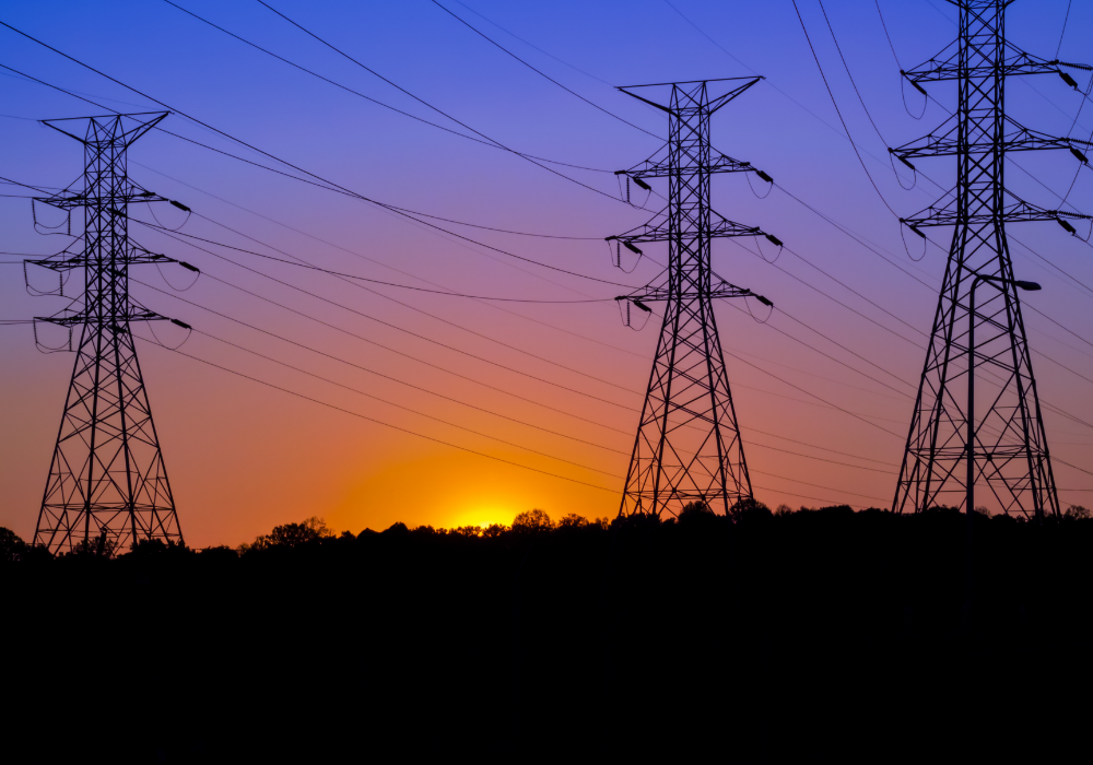 Open landscape, electricity pylons, power lines crisscrossing sunset sky, evening colors, editorial travel photo, no people.
