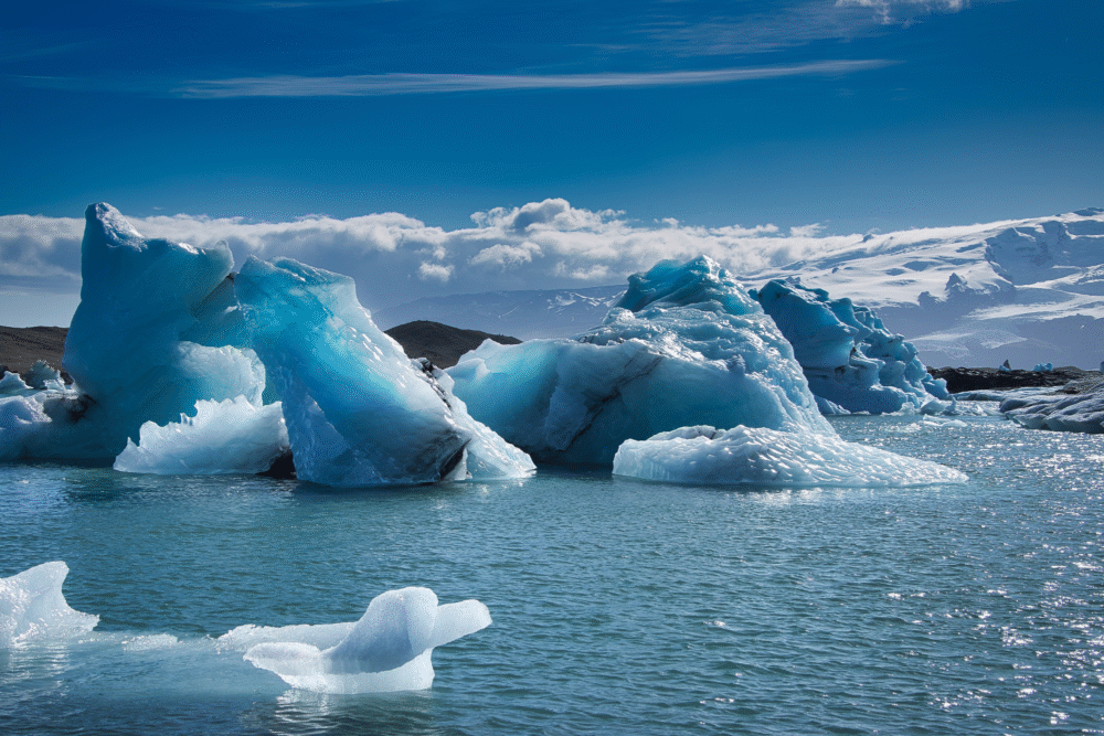 Glacial lake, massive blue-white icebergs, wide view, soft daylight, editorial travel photo, no people.
