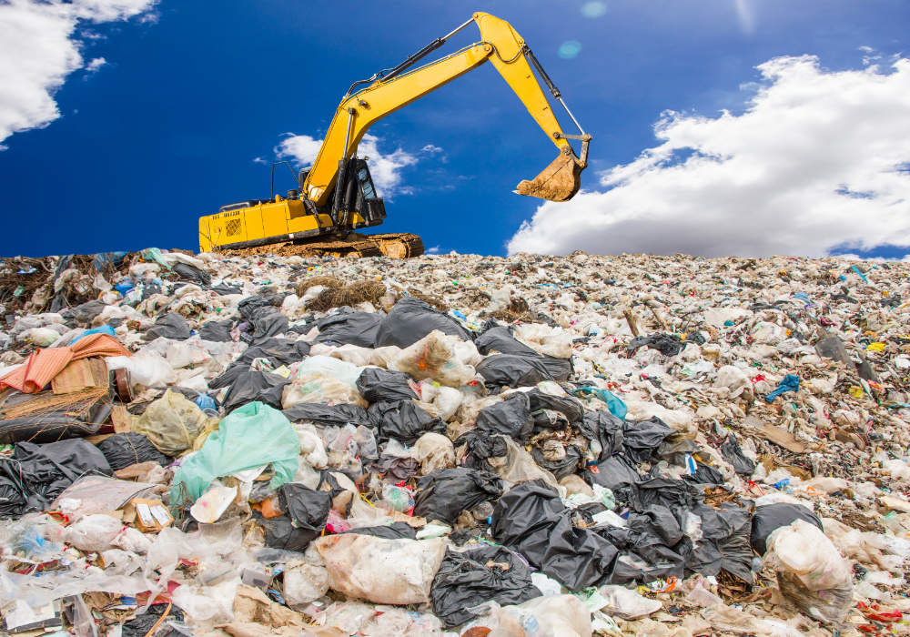 Landfill, yellow excavator, wide heaps of mixed waste, midday sunlight, documentary style, no people.